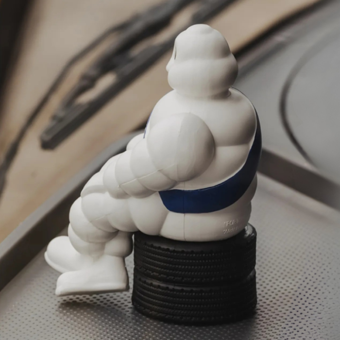 Michelin pop zittend op autobanden geplaatst op een dashboard.